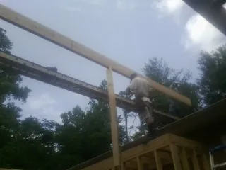 Carpenter setting a ridge beam over a new addition frame — Ice Dam Removal by Roofing Brothers in Archie