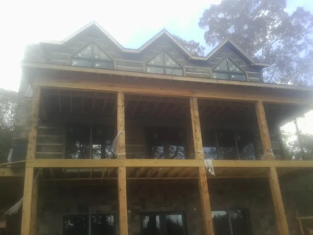 Dormers and porch framing on a large log home under construction — Roof Coating work by our crew in Archie