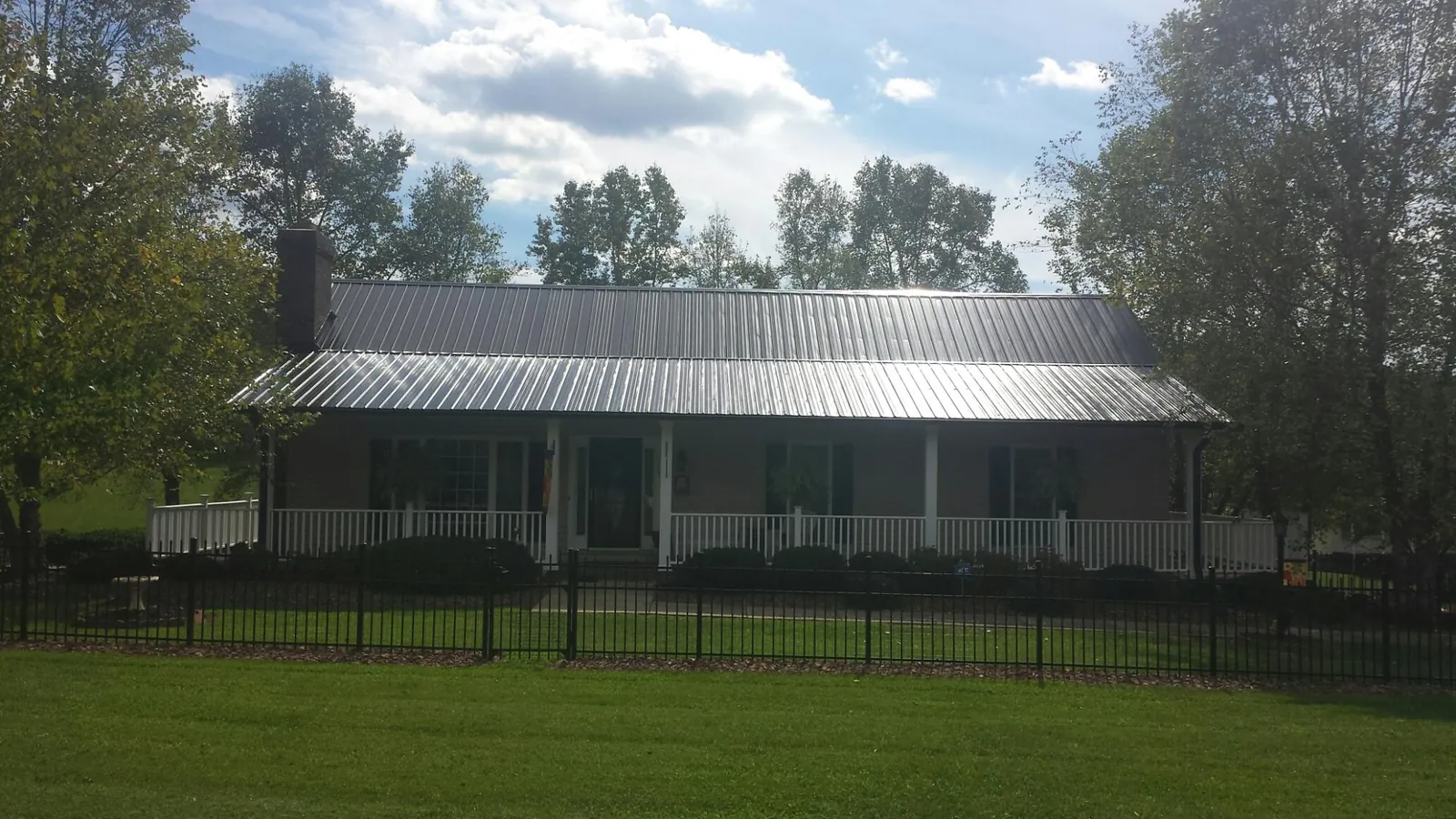 Gray metal roof on a brick ranch with a full width front porch — Gutter Guard Installation work by our crew in Archie
