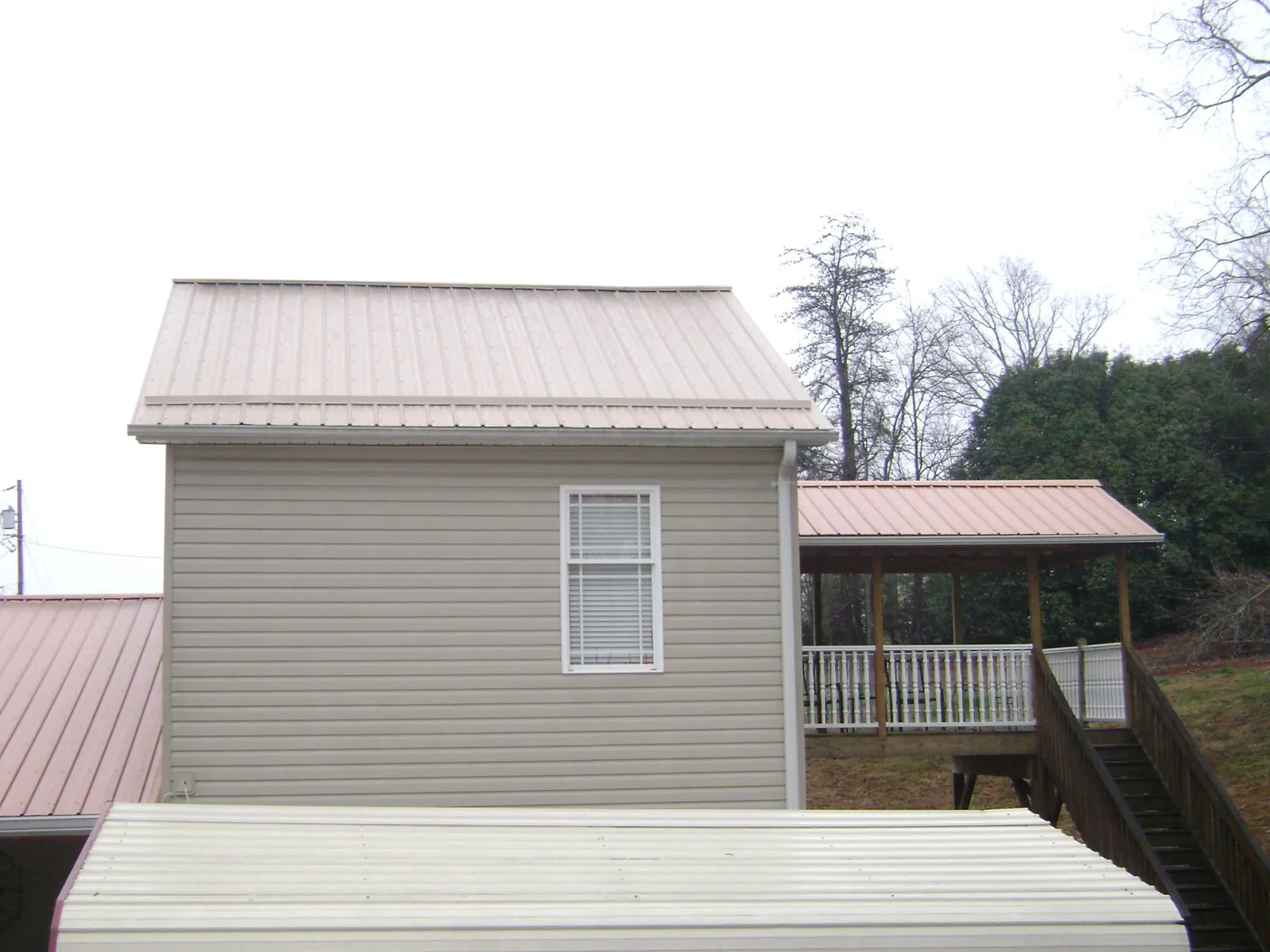Tan metal roofs on a two story addition and attached porch, from a Roof Replacement job in Archie